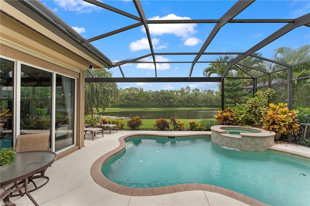 View of swimming pool with an in ground hot tub, a patio, and glass enclosure