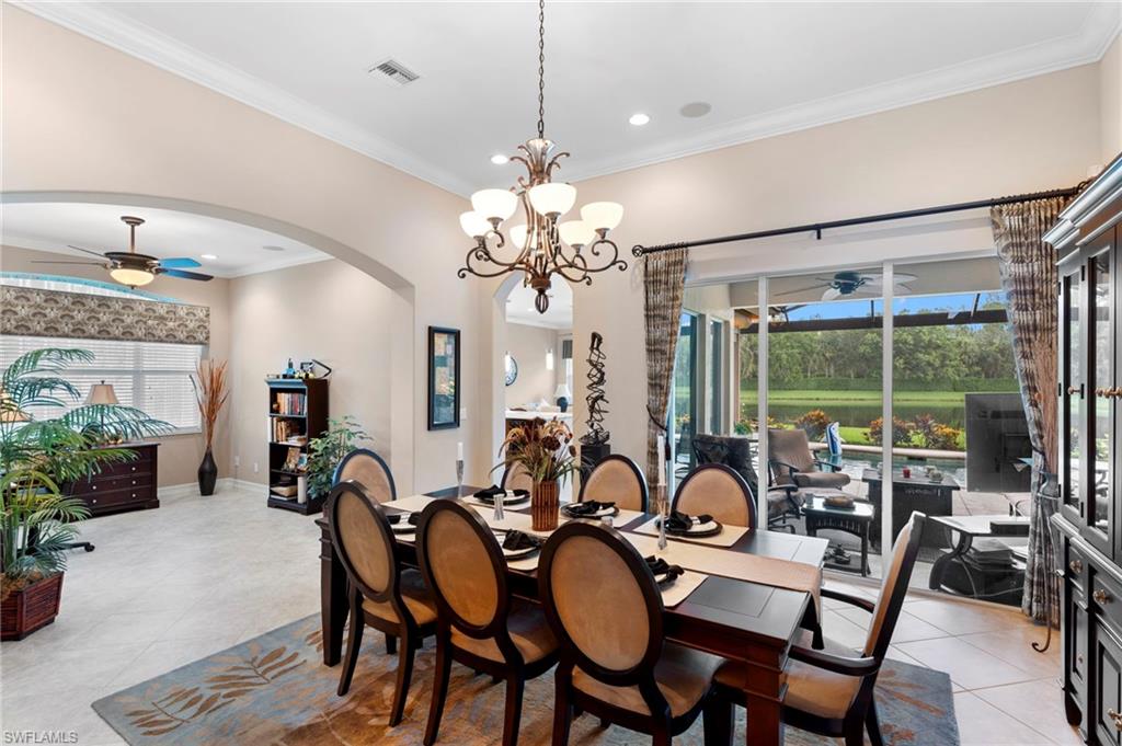 Dining room featuring ornamental molding, ceiling fan with notable chandelier, and light tile patterned floors