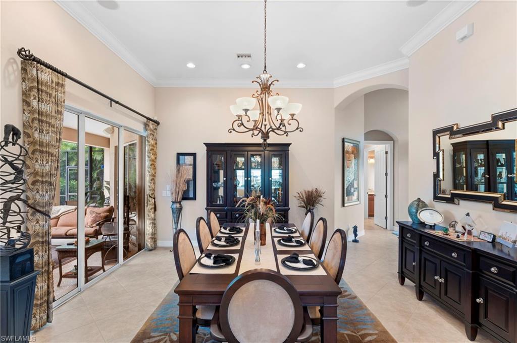Dining space with a chandelier, french doors, crown molding, and light tile patterned floors