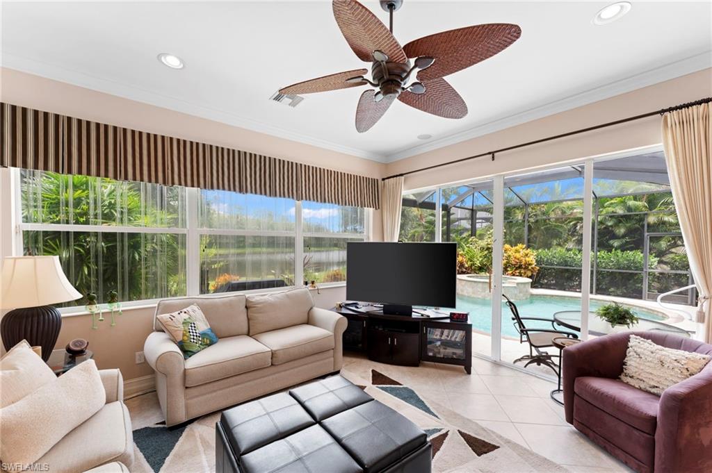 Living room featuring light tile patterned floors, crown molding, and ceiling fan