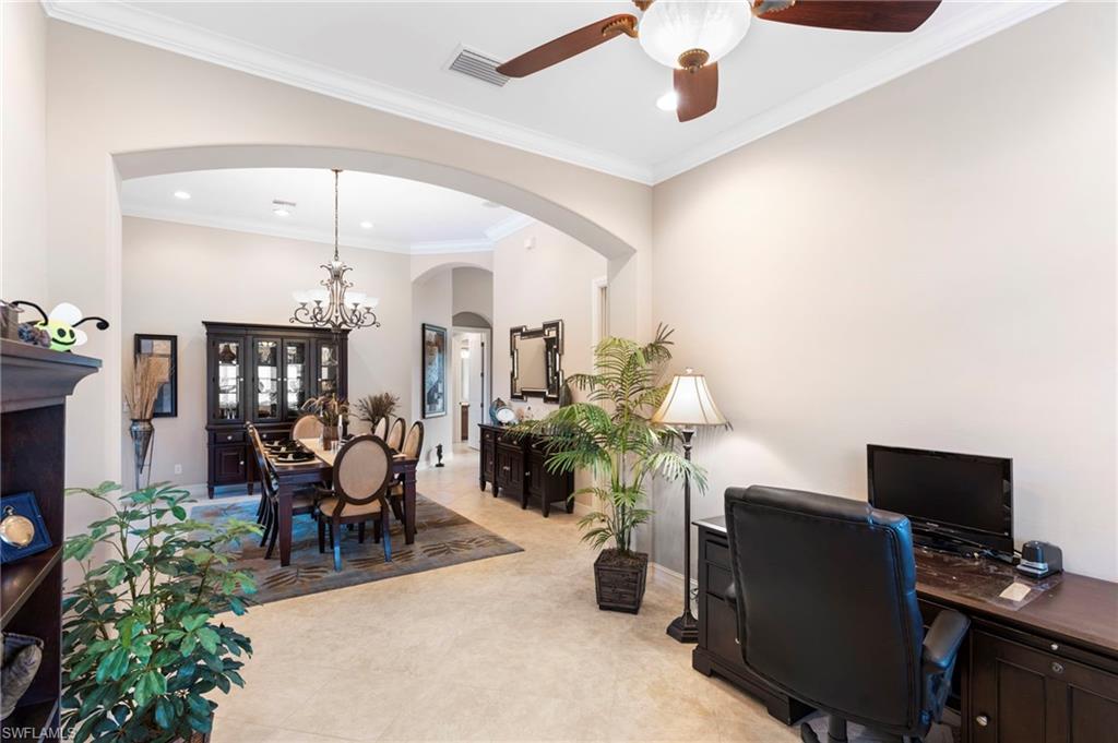 Home office with light tile patterned flooring, ceiling fan with notable chandelier, and crown molding