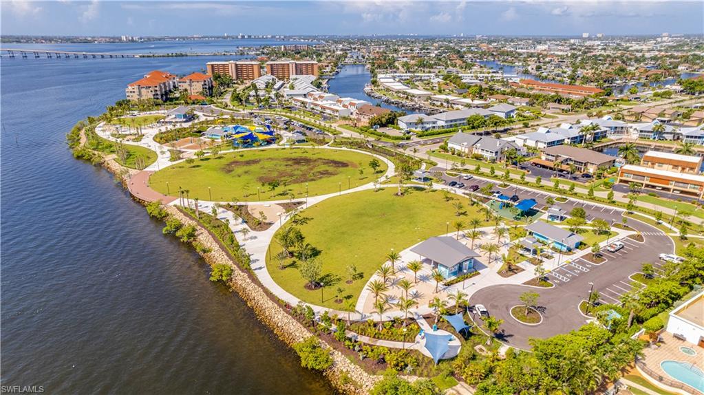 Jaycee Park-Expansive waterfront park area featuring pedestrian pathways, extensive green spaces, a water park with slides, dedicated parking areas, and mature palm trees