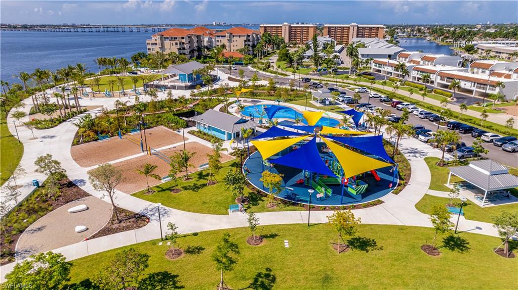 Jaycee Park-Expansive outdoor recreational area featuring a contemporary playground with colorful shade structures, multiple sand volleyball courts, a splash pad, walking paths, and mature landscaping