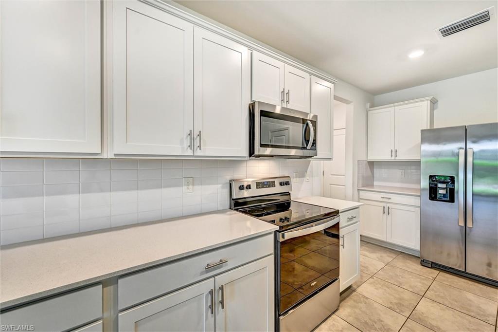 Well-appointed kitchen featuring stainless steel appliances including a built-in microwave, smooth cooktop range, and ample upper and lower cabinet storage with a clean, contemporary finish.