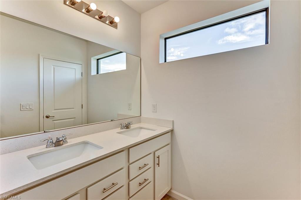 Primary bathroom with a wide double-sink vanity, designer fixtures, backlit mirror, and high-end tile work — a serene retreat designed for comfort and elegance.