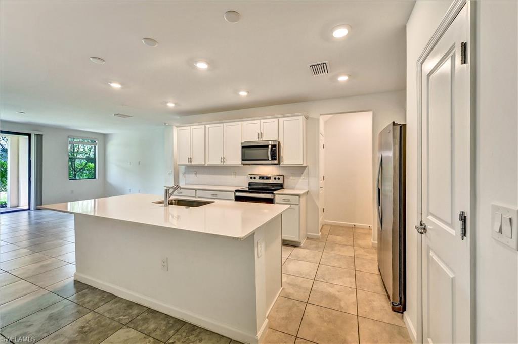 Gourmet chef's kitchen at 1519 Lake Jessup featuring an oversized center island, white shaker cabinetry, stainless steel appliances, and premium wood-look flooring — perfect for entertaining.