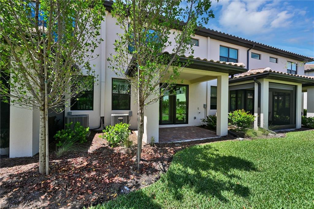 Rear exterior view of this stunning two-story home showcasing the covered patio, mature tropical landscaping, and architectural details that make 1519 Lake Jessup a truly exceptional property.