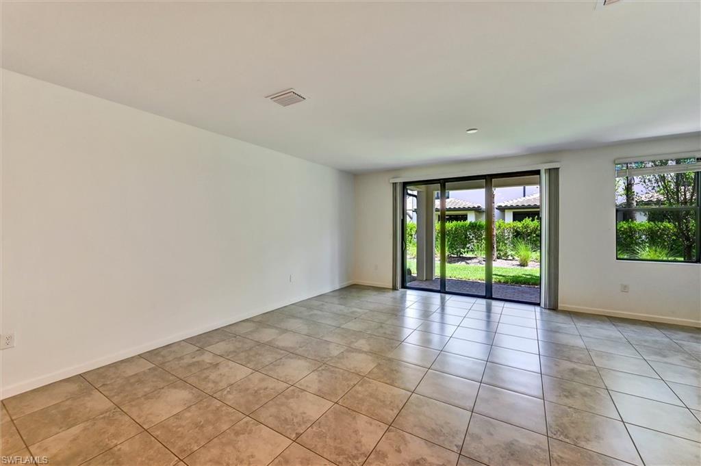 Expansive great room with soaring ceilings, recessed lighting, wide-plank tile flooring, and oversized sliding glass doors that open to the outdoor patio — perfect for indoor-outdoor Florida living.