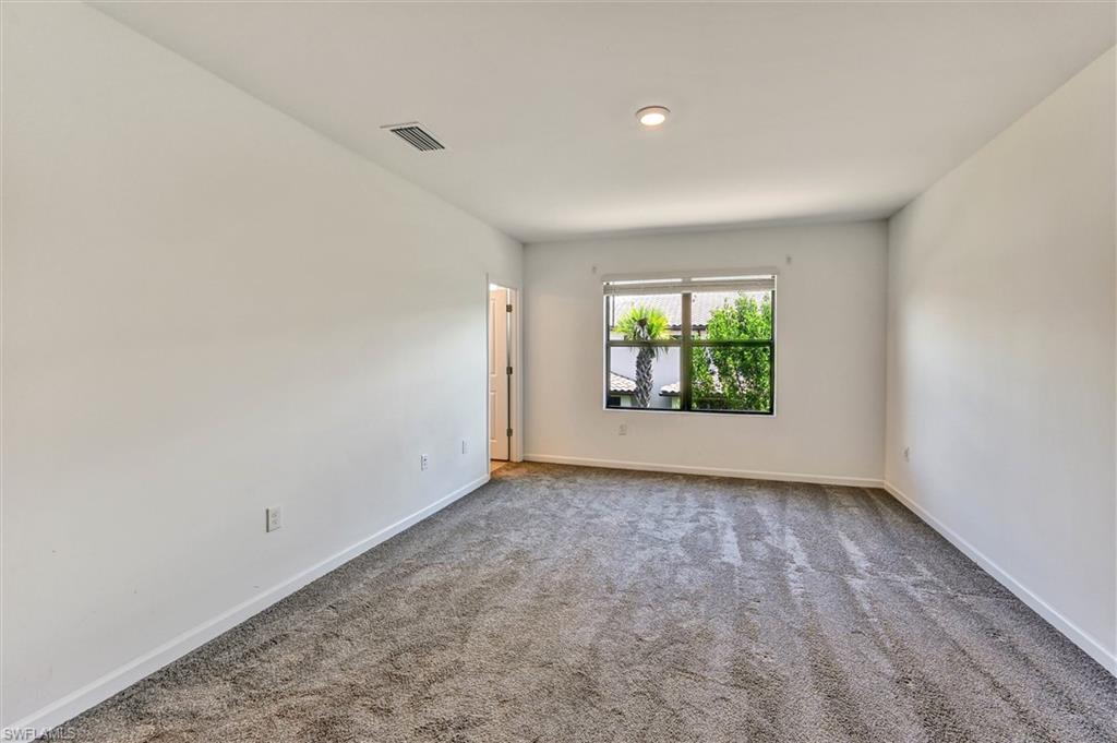 Generous secondary bedroom with plush carpet, ample natural light, and neutral paint tones — a comfortable and versatile space suitable as a guest room, home office, or kids' room.