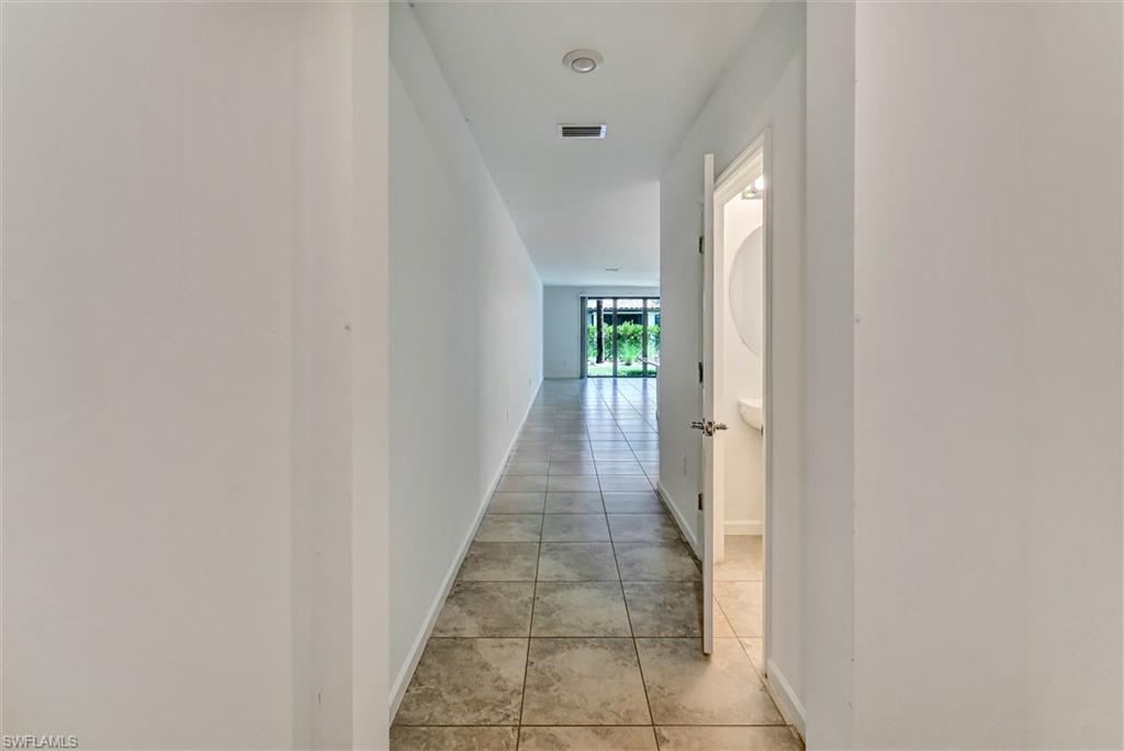 Bright interior hallway connecting the main living areas and bedrooms with clean lines, recessed lighting, and neutral finishes throughout this well-designed home.