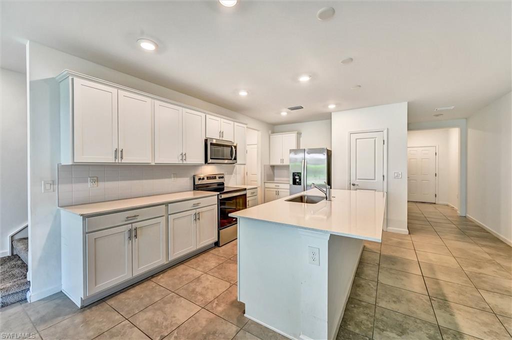 Spacious open-concept kitchen with white cabinetry, quartz countertops, stainless steel appliances, and abundant natural light, ideal for home chefs and families alike.