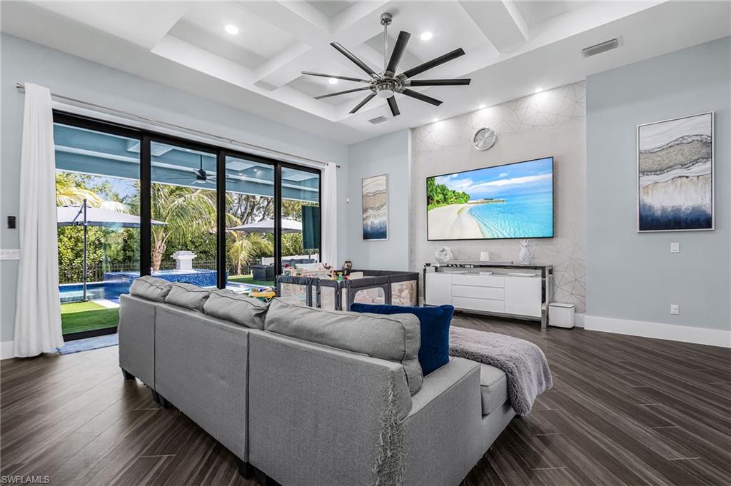 Spacious living area featuring wood-finish flooring, a coffered ceiling with recessed lighting, and a modern ceiling fan