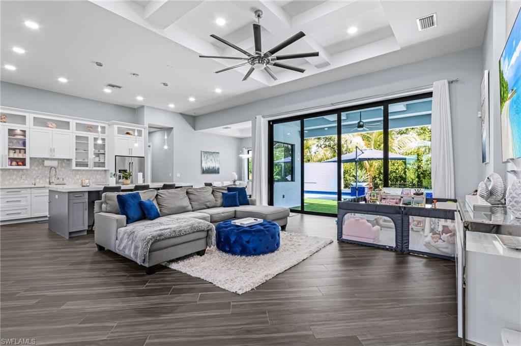 Spacious living area featuring coffered ceilings, recessed lighting, and wood-finish flooring