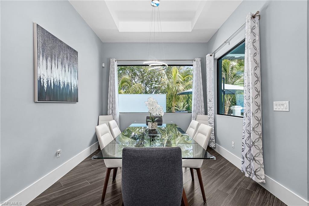 Dining area featuring a tray ceiling, contemporary chandelier, recessed lighting, and large windows