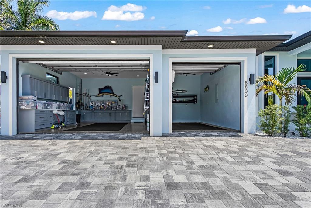 Paver driveway leading to a two-bay garage with overhead doors