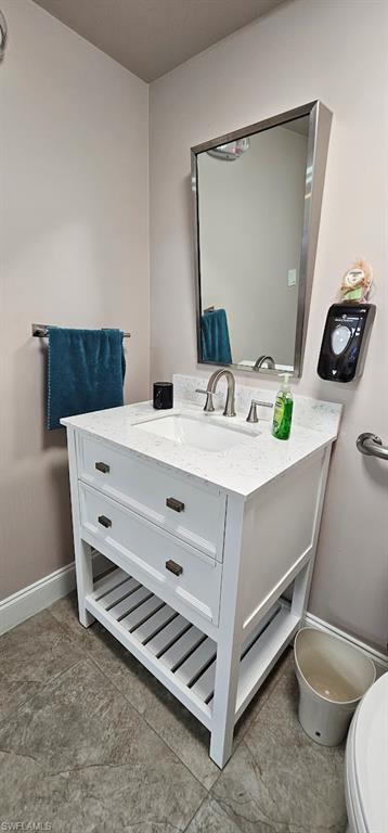 White vanity with a built-in sink and stone-finish countertop, brushed nickel faucet, and a wall-mounted rectangular mirror