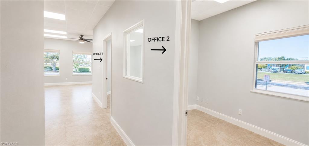 Hallway featuring tile flooring, neutral wall tones, white trim, and a window opening to an interior room