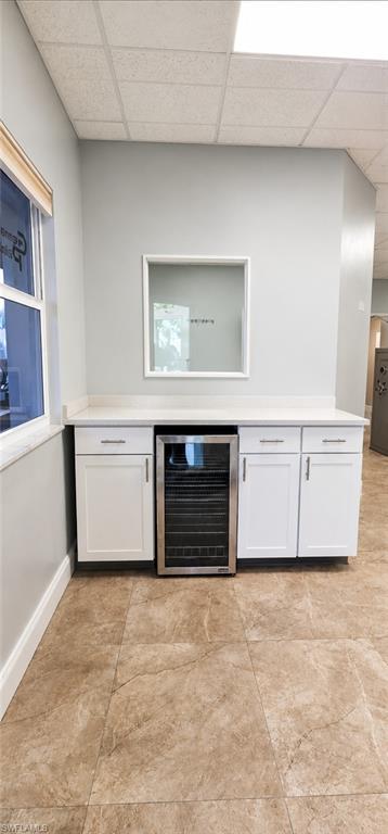 Built-in cabinetry with a beverage refrigerator, light-toned countertop, and tiled flooring