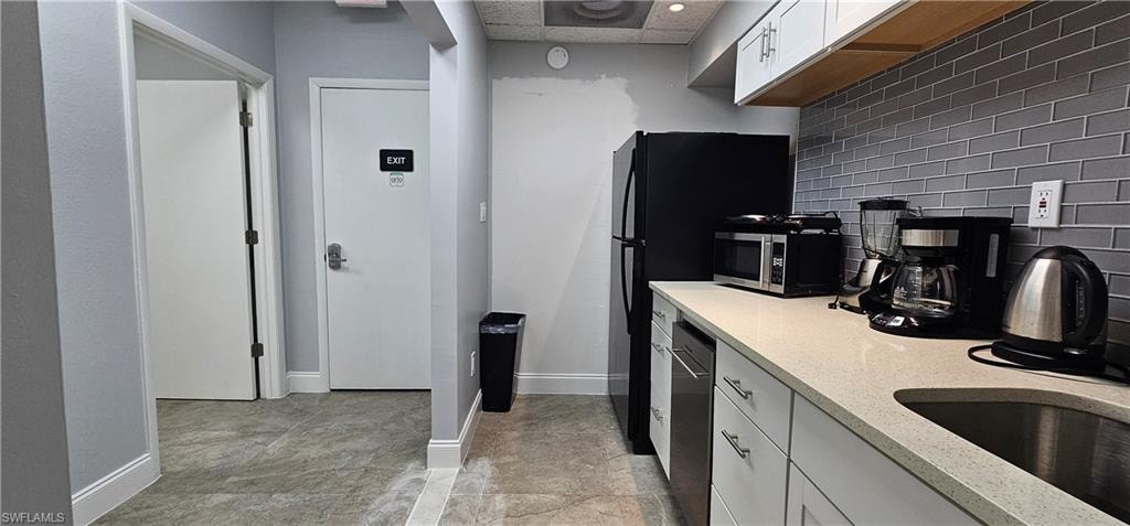 Integrated kitchenette with white cabinetry, light countertops, and a gray subway tile backsplash