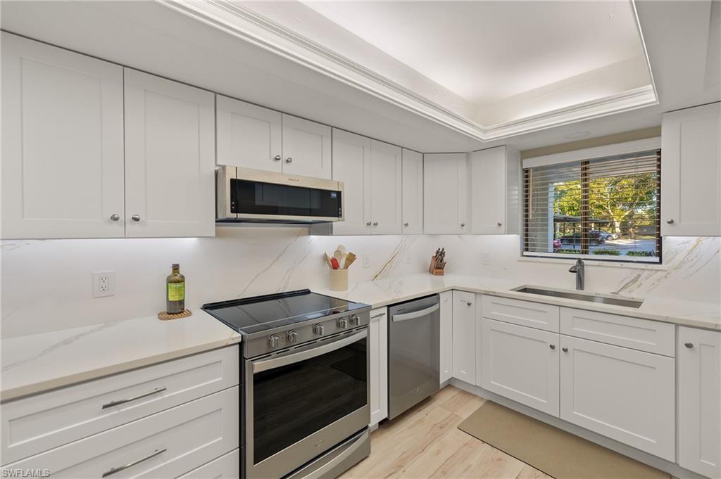 Kitchen featuring white cabinetry, sink, light wood-type flooring, and appliances with stainless steel finishes