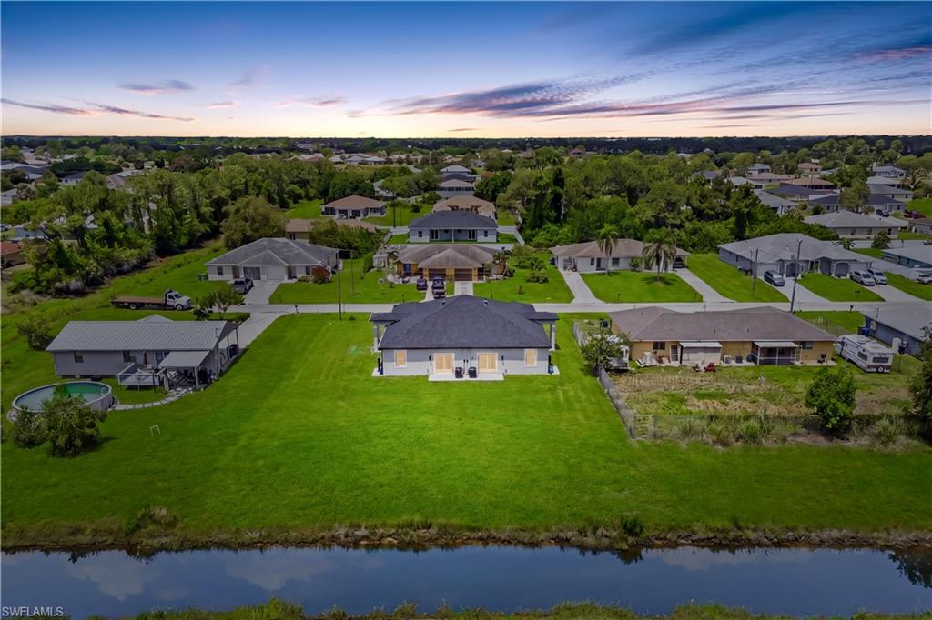 Scenic backyard perspective featuring both units and lush canal backdrop.