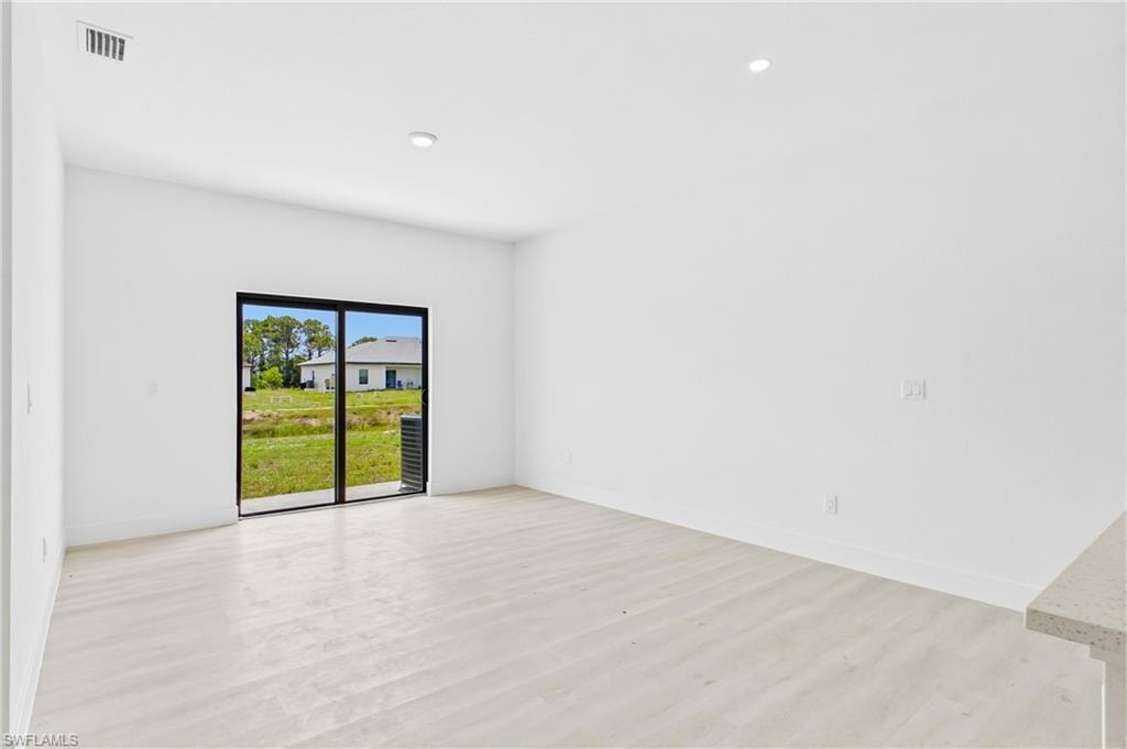 Open-concept living area with high ceilings, vinyl flooring, and abundant natural light flowing throughout the space.