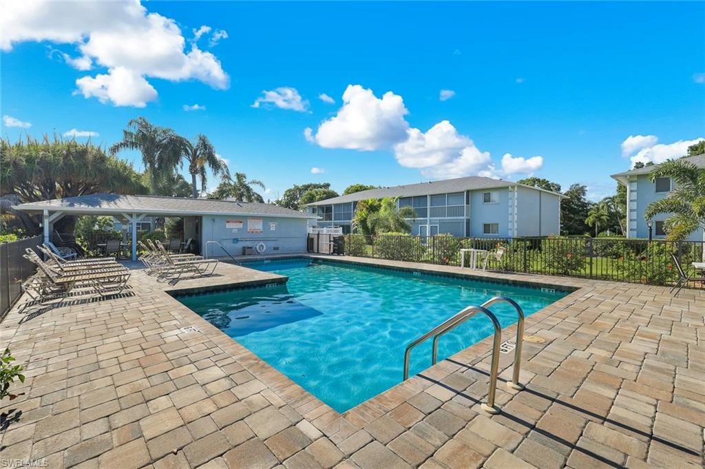 Resort-style pool with paver decking, fenced perimeter, and covered patio structure
