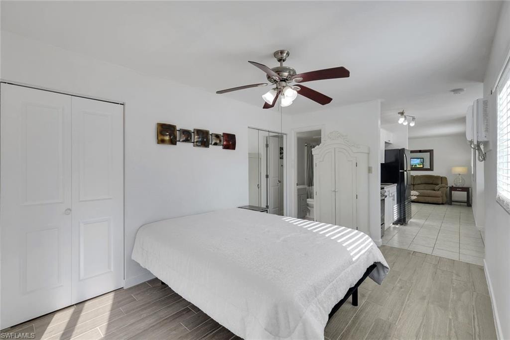 Wood-finish flooring, ceiling fan with integrated lighting, bi-fold closet doors, white paneled walls, and privacy blinds