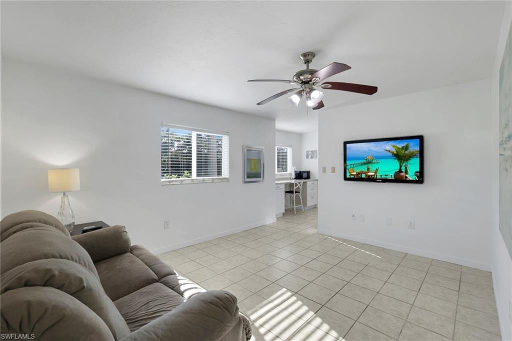 Bright, open living area featuring tile flooring, a ceiling fan with integrated lighting, and a wall-mounted flat-screen television
