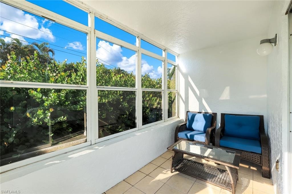 Bright, light-filled sunroom with expansive multi-pane windows framing lush tropical landscaping
