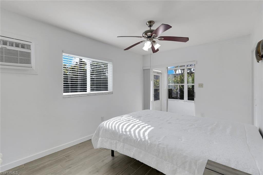Wood-finish flooring, white walls, and a ceiling fan with integrated lighting