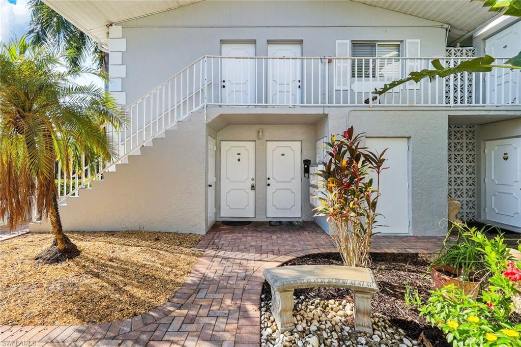 Gray stucco exterior with white double doors, a white exterior staircase, and a white balcony railing