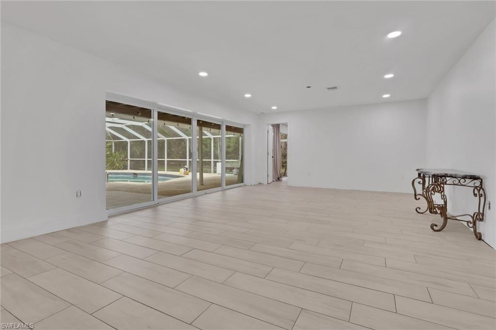 Spacious interior featuring light-toned plank flooring, recessed lighting, and expansive sliding glass doors