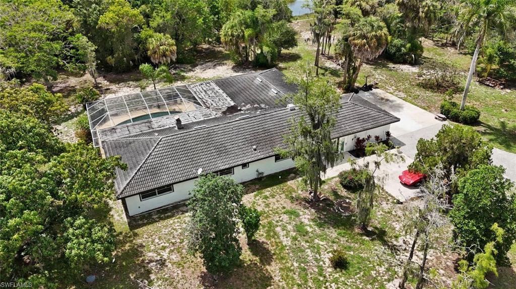 Single-story residence featuring a tile roof, screened enclosure, and concrete driveway