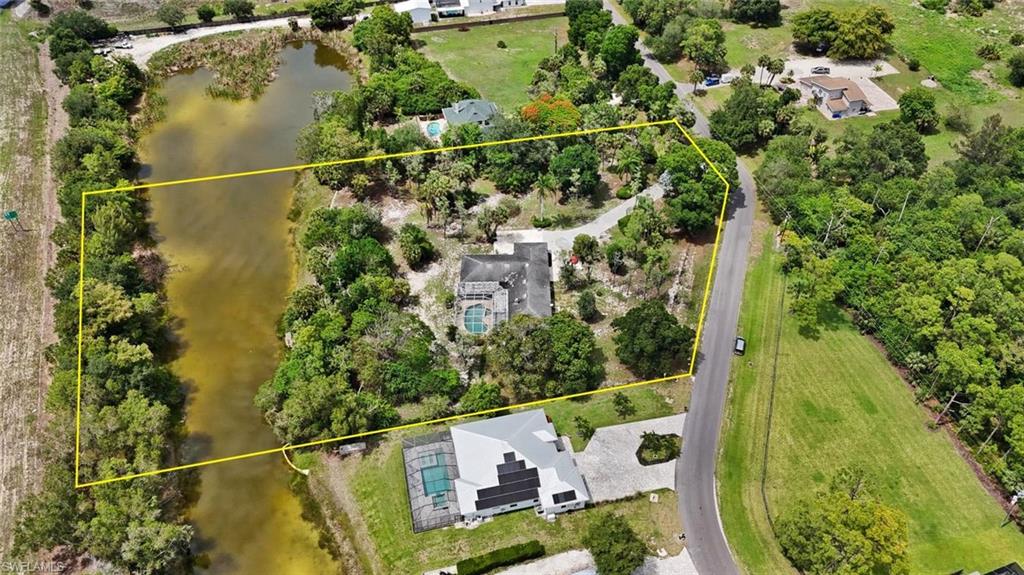 Expansive property featuring a private water frontage, lush landscaping, mature trees, and a private driveway