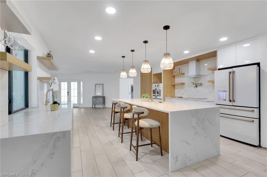 Contemporary kitchen featuring a spacious island with seating, integrated appliances, and light wood-finish flooring