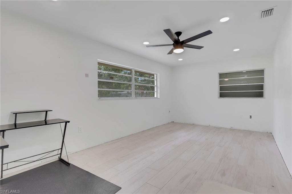 Spacious room featuring light wood-finish flooring, recessed lighting, and a contemporary ceiling fan
