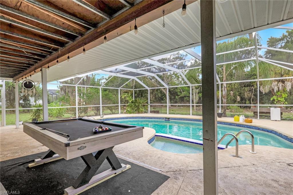 Screened lanai featuring a swimming pool, integrated spa, and concrete decking