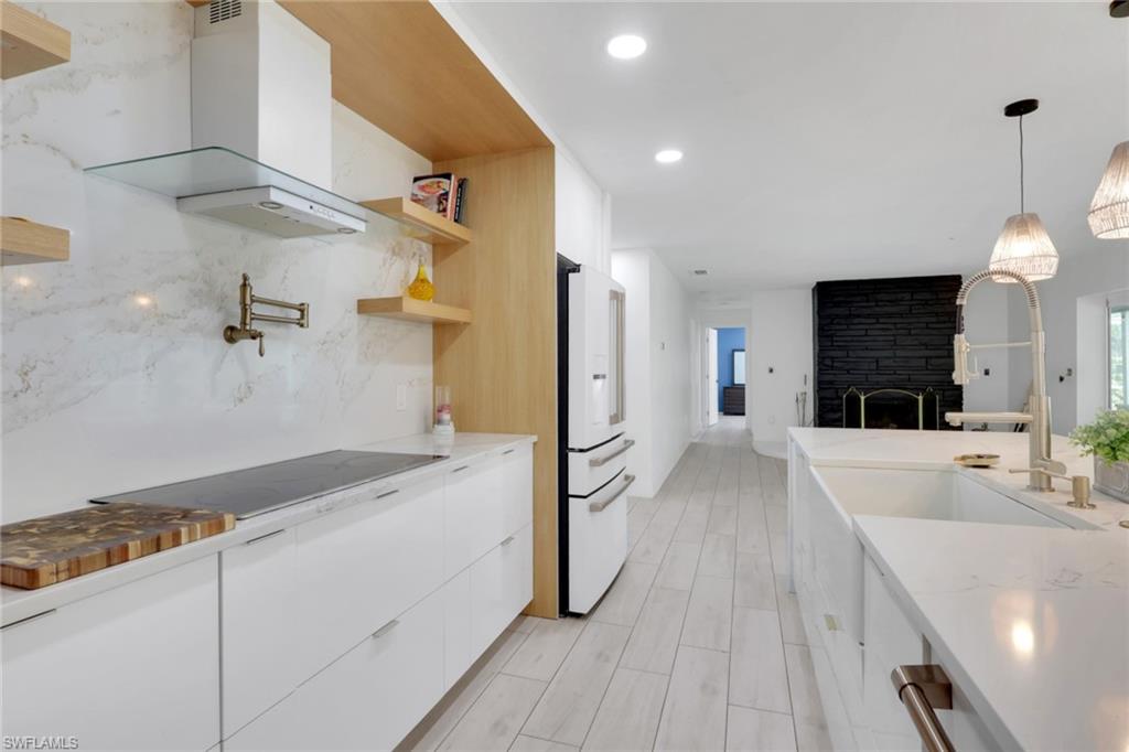 Modern kitchen featuring white flat-panel cabinetry, a built-in induction cooktop, and a matching white range hood