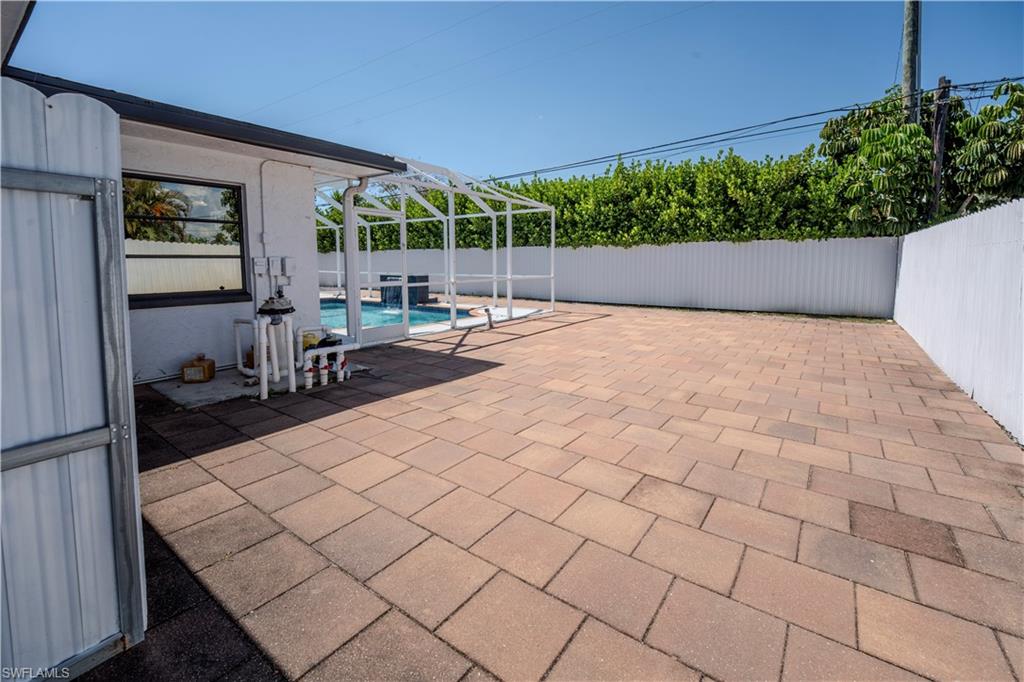 Expansive paver patio surrounding a screened pool enclosure with a water feature