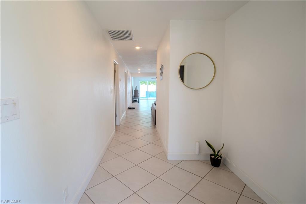 White interior walls with recessed lighting and diamond-patterned tile flooring