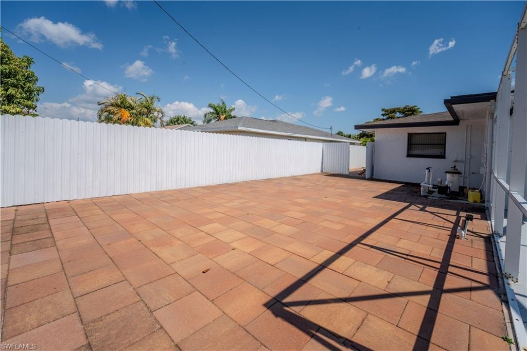 Expansive paver patio with a white privacy fence