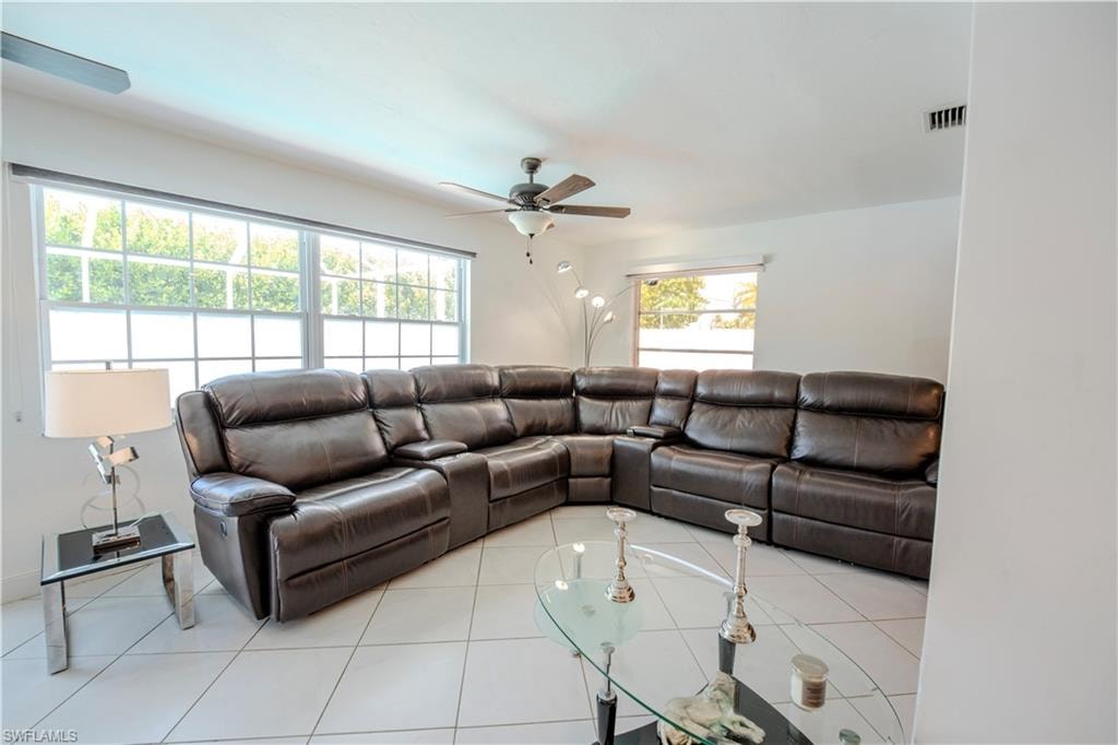 Expansive living area featuring tile flooring, multiple windows, a ceiling fan with integrated lighting, and recessed lighting