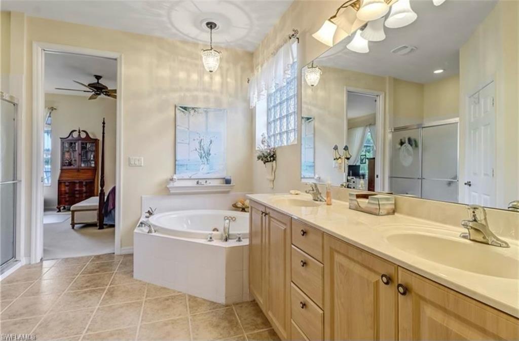 Bathroom with ceiling fan, shower with separate bathtub, vanity, and tile patterned floors