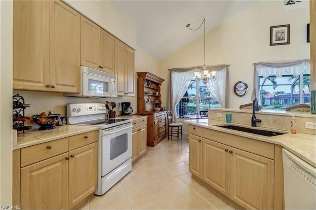 Kitchen with sink, a notable chandelier, white appliances, light tile patterned floors, and pendant lighting