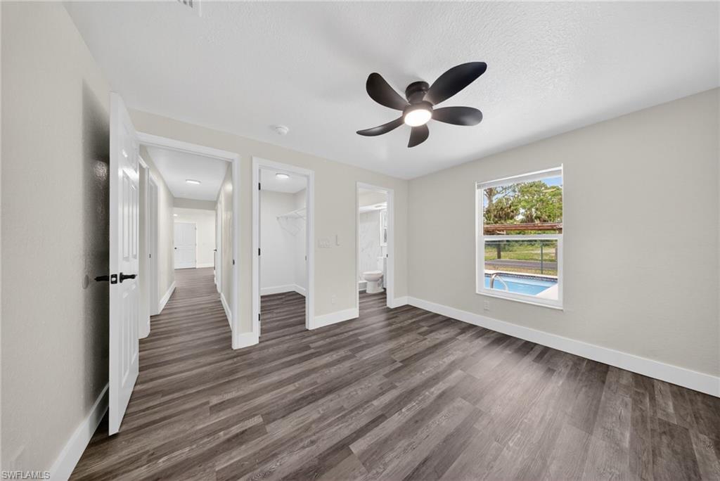 Spacious room featuring wood-finish flooring, light gray wall paint, and a modern ceiling fan