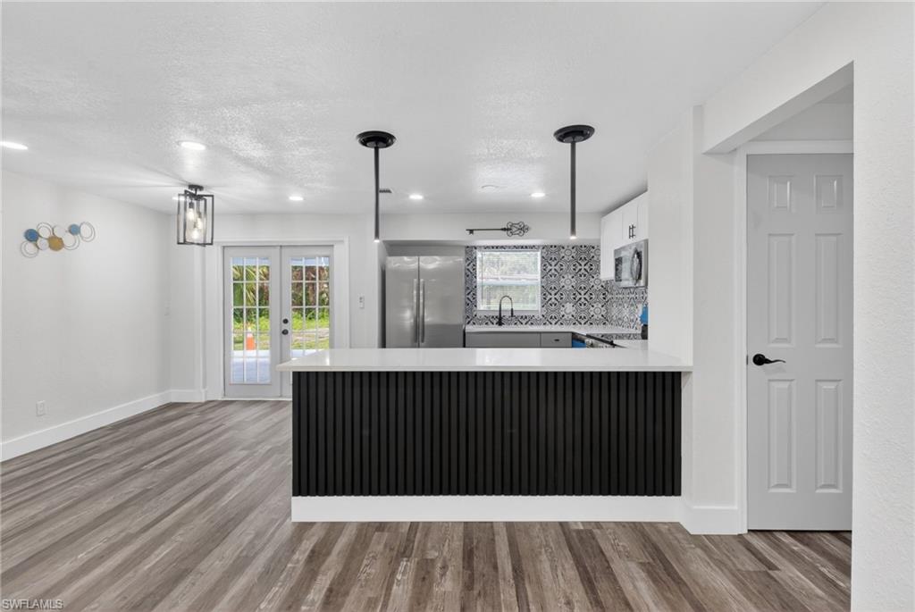 Kitchen island with a slatted black base and white countertop, featuring two pendant lights