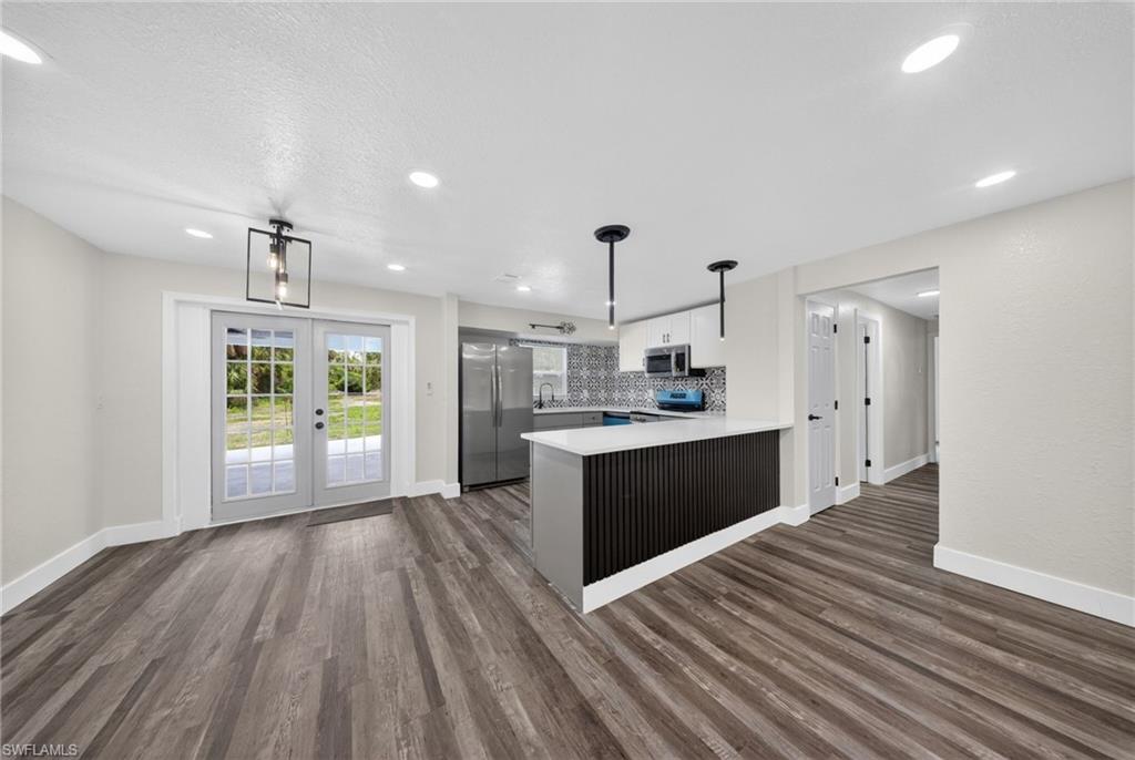 Open-concept living space featuring wood-finish flooring, recessed lighting, and a kitchen island with pendant lighting
