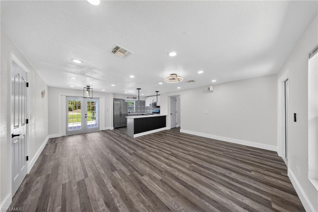 Spacious open-concept living area featuring wood-finish flooring, recessed lighting, and a contemporary ceiling fan