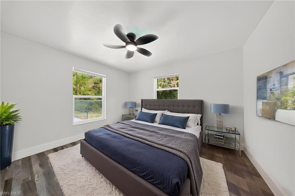 Bedroom featuring wood-finish flooring, two windows, a ceiling fan, and white baseboards